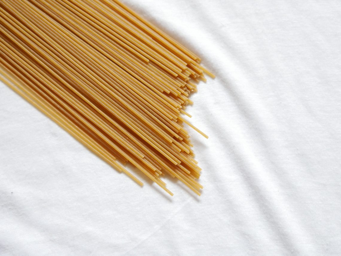 Spaghetti crudi messi in diagonale su sfondo bianco